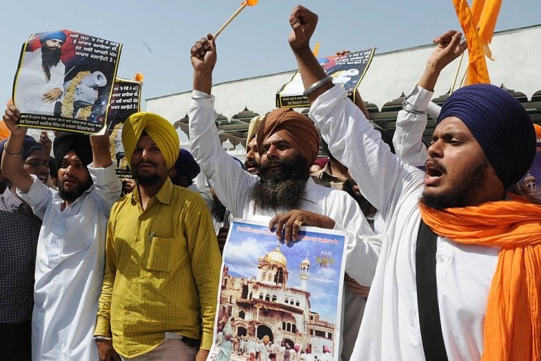 Men holding posters with pictures of the Golden Temple in India gather during a protest.