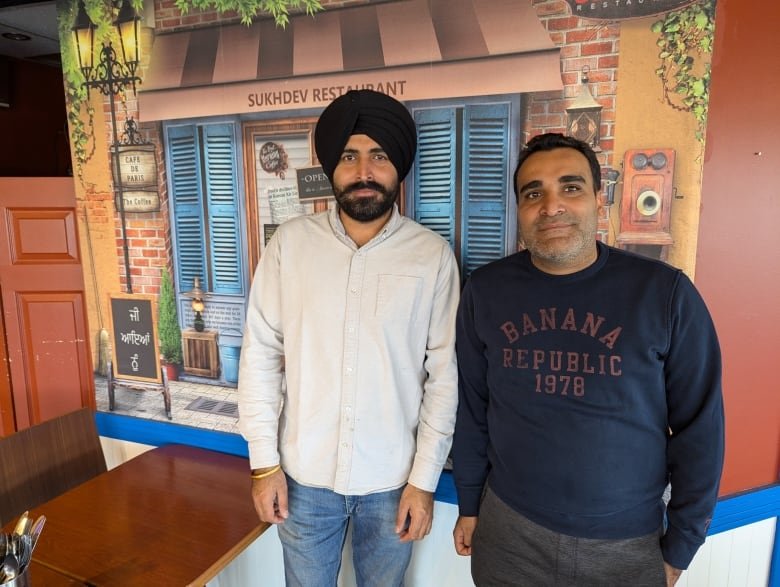 Two men standing in a restaurant.