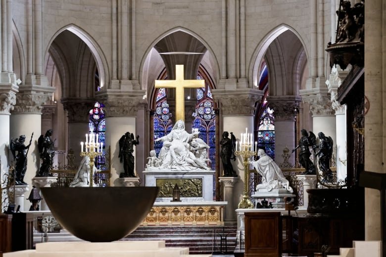 The ornate interior of a Catholic church is shown, with an altar, cross and stained glass windows.