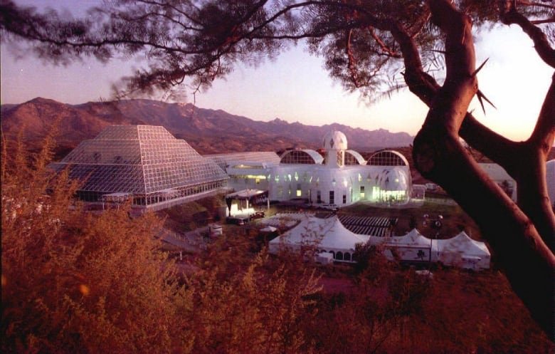 A futuristic looking glass and metal building stands in the desert.