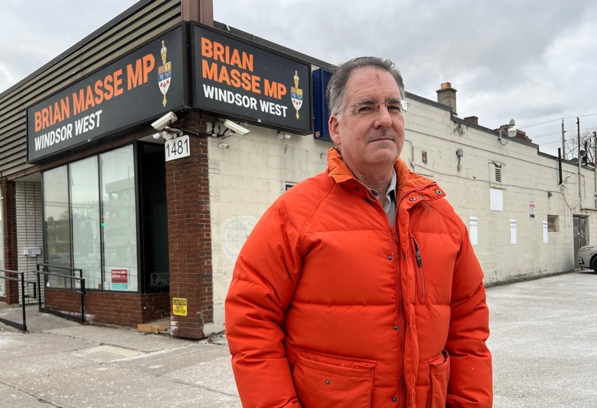 brian-masse Man in orange jacket standing outside a building.