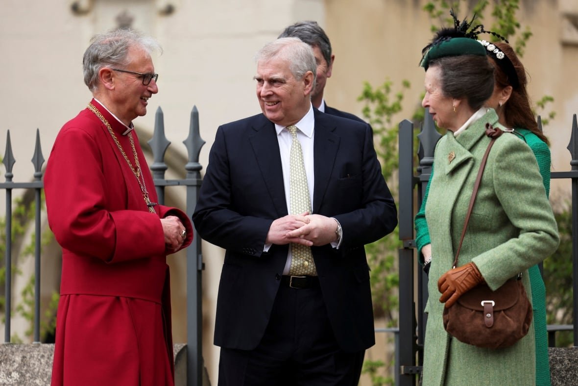 People talk with a member of the clergy outside a chapel.