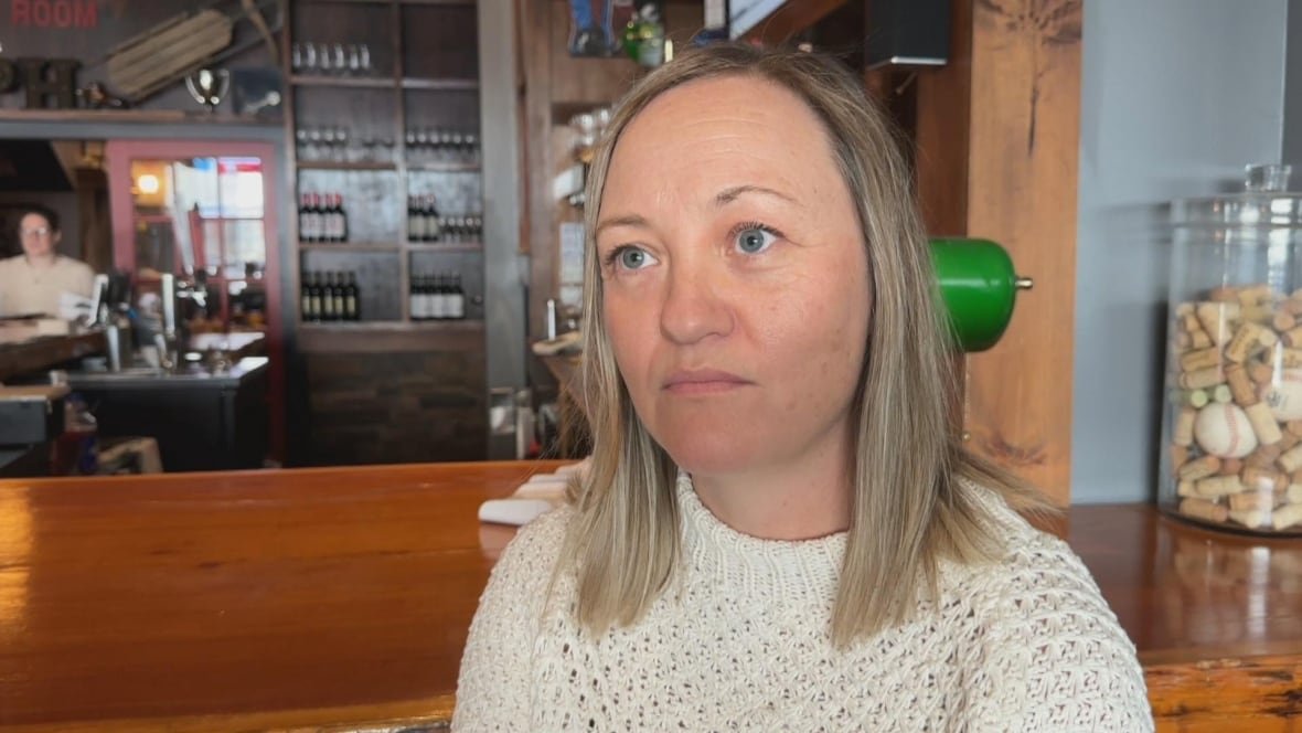 Woman sits in front of a bar.