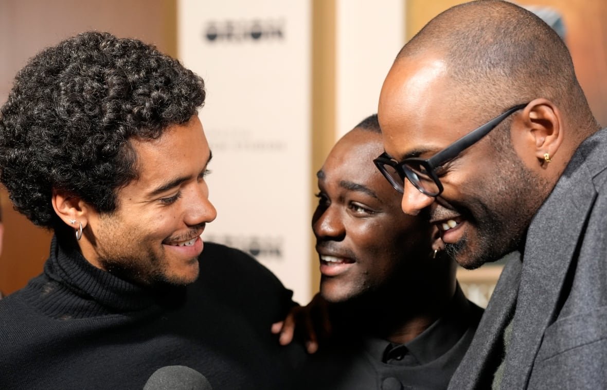 A close up image of three men laughing is shown.