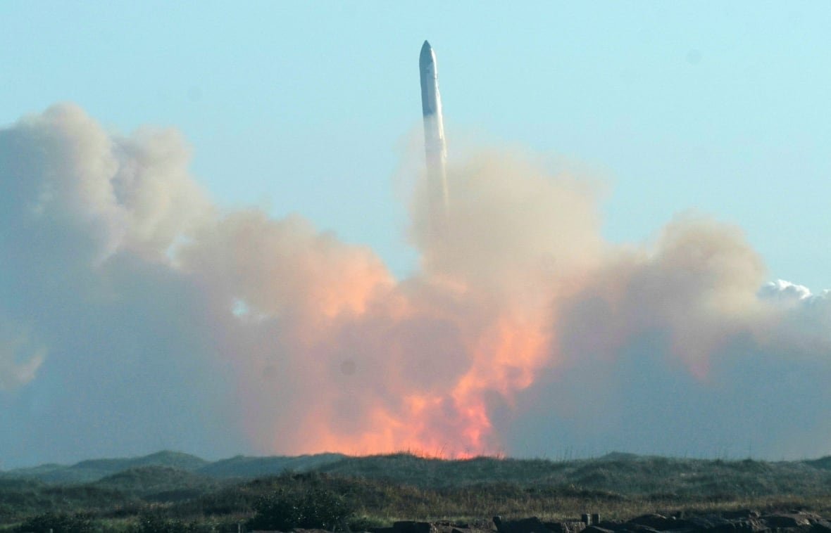 A space capsule is seen lauching into air against a blue sky.