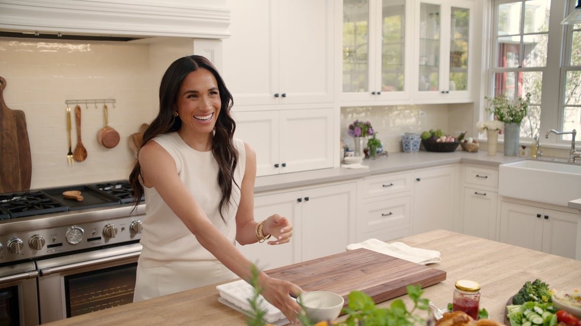 A woman  in a white dress stands in a white kitchen