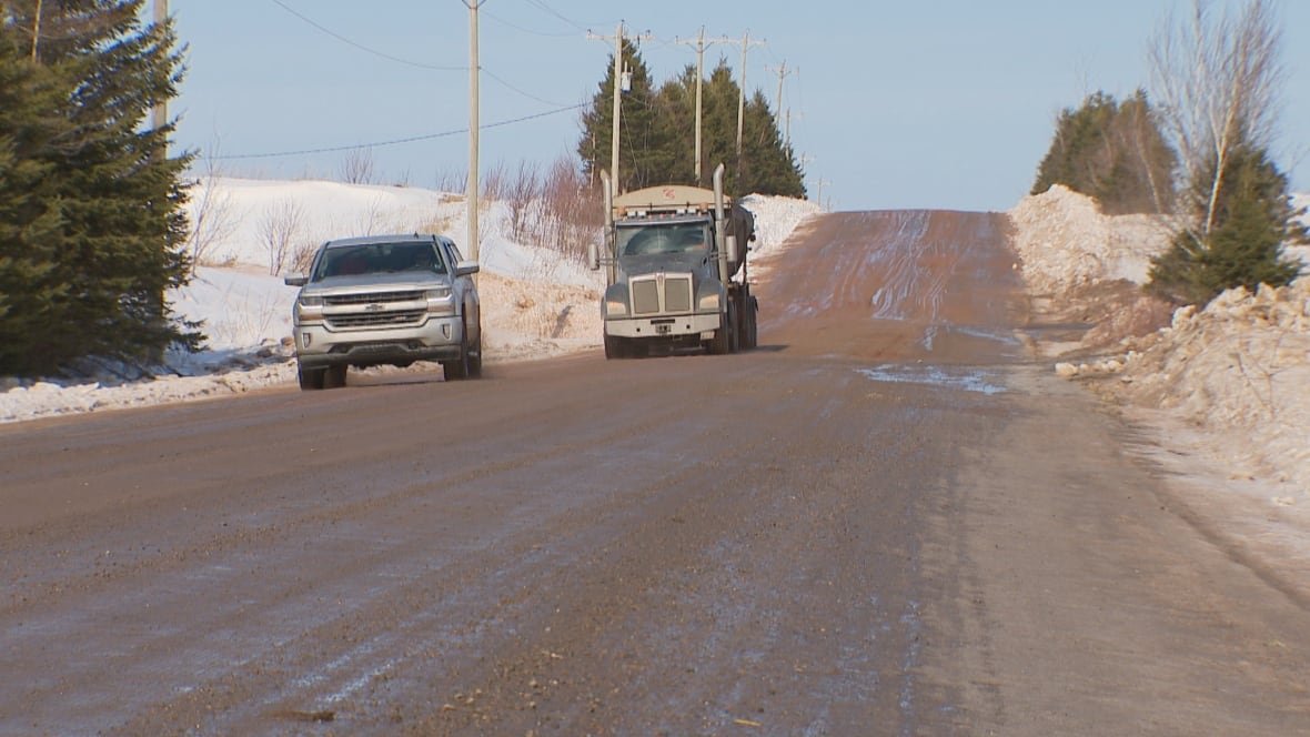 greenfield-road-pei-feb-2025 A wide picture of two trucks driving down a muddy, unpaved road.