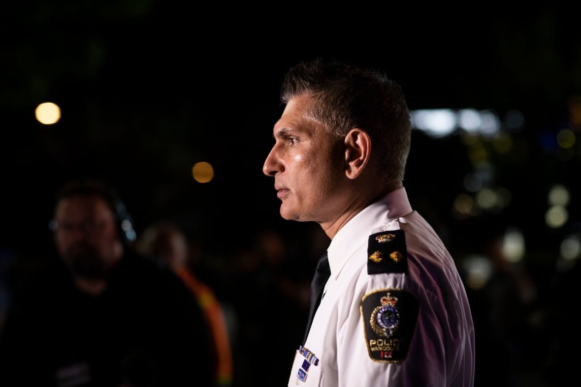 A man wearing a white police uniform is pictured in profile at night.