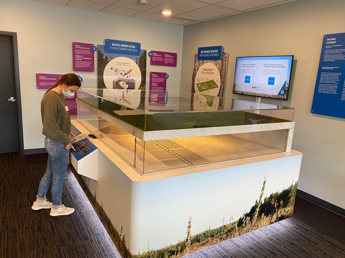 ignace-deep-geological-repository-model A person looks at a three-dimensional model in a glass display case.