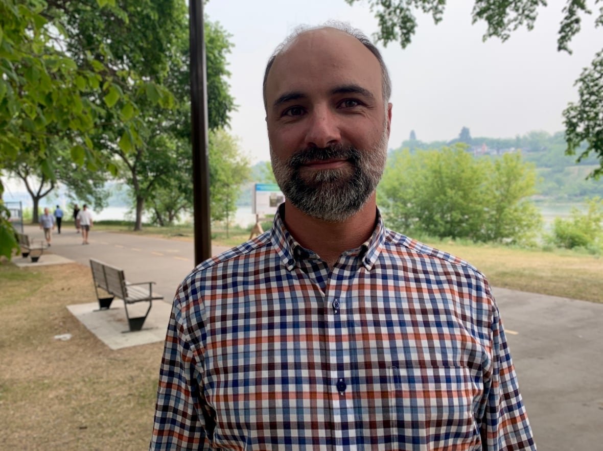 jean-michel-devink A man poses for a photo during the day in a park near a riverbank.