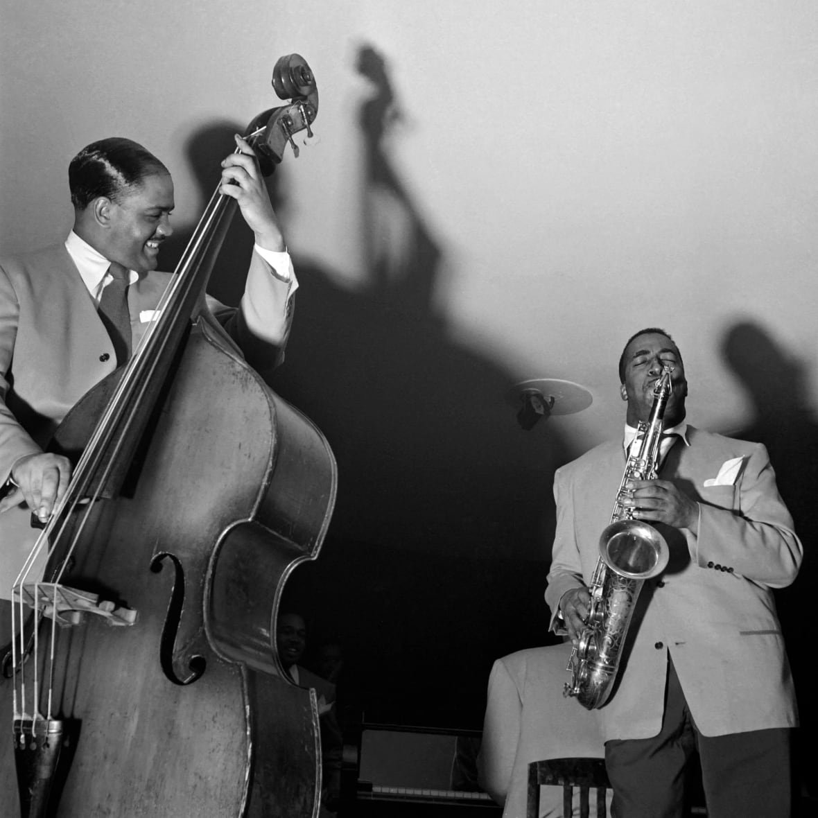 494451888-jazz-orchestra Black and white image of two bBack men in suits, one on saxophone and one on stand-up bass, jamming together