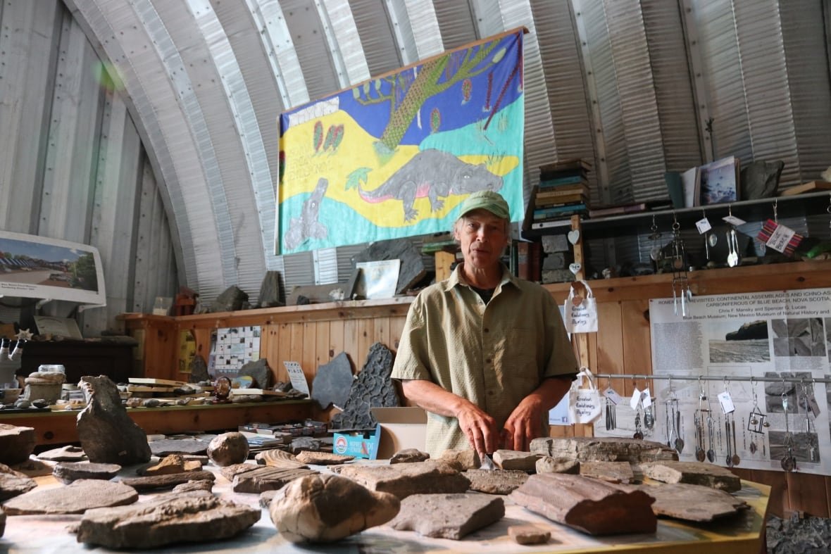 chris-mansky-blue-beach A man stands behind a large collection of rocks and fossils.