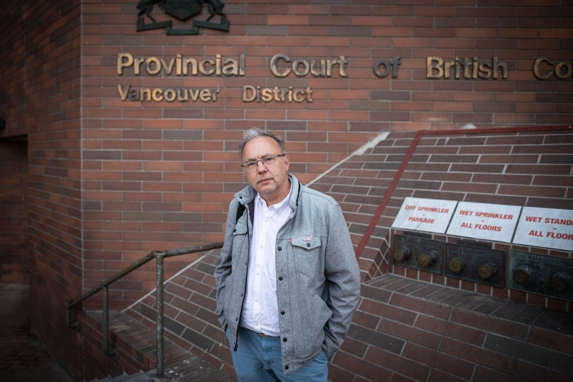 christopher-seres-1 A man with salt and pepper hair and glasses, stands with his hands in his pockets in front of the provincial courthouse in Vancouver.