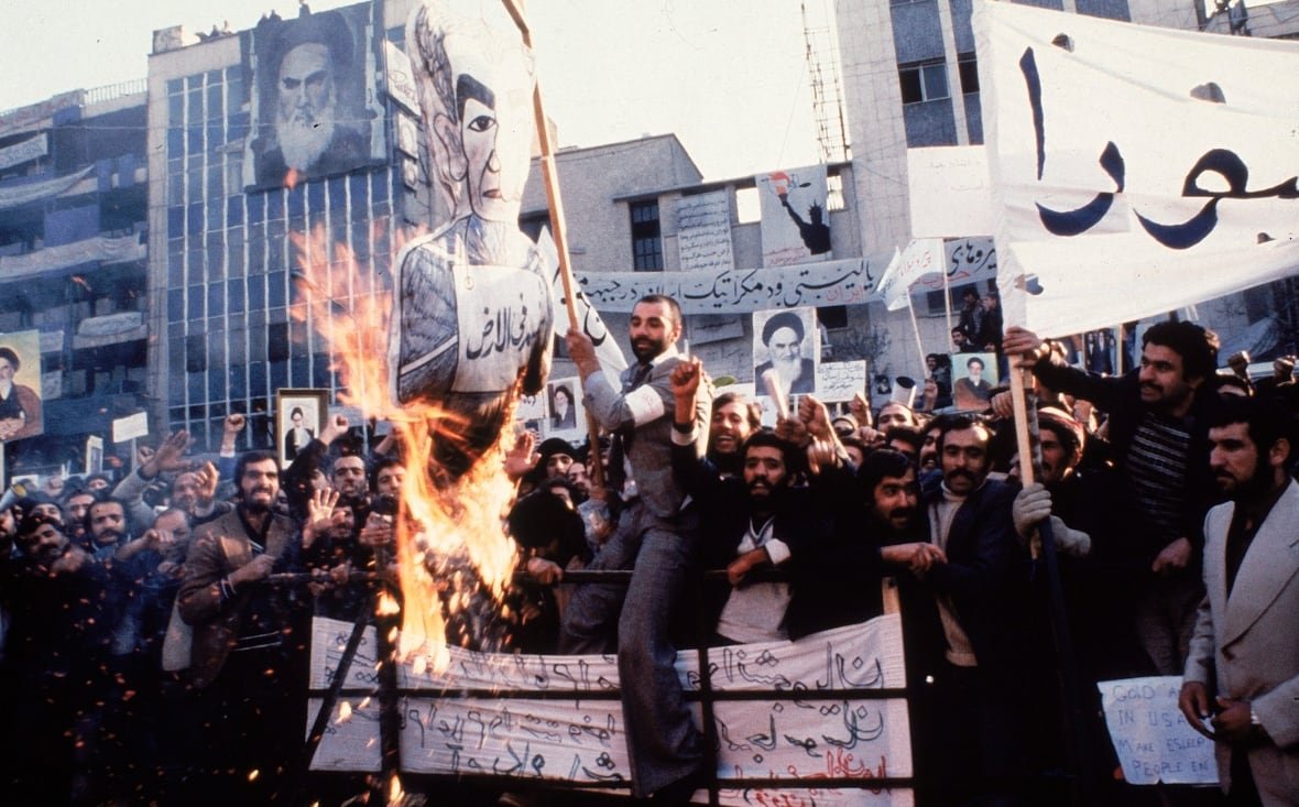 iran-revolution-anniversary-timeline People burn effigies of a man in a protest in an archival picture.