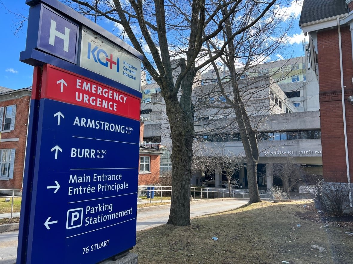 kingston-general-hospital A blue and red sign shows directions to different hospital wings, along with the emergency department and parking. The hospital can be seen in the background.