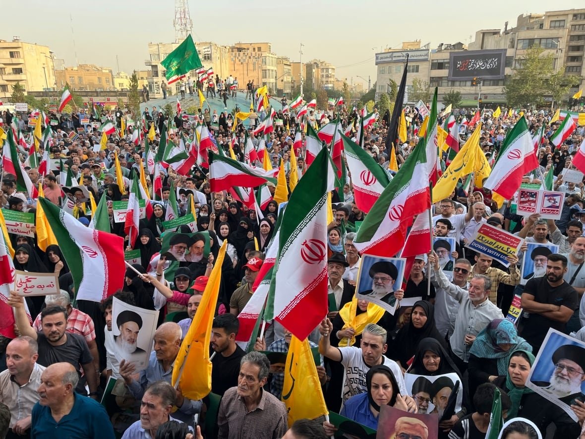 protesters-carrying-iranian-national-flags-in-tehran A protest in Tehran, with people holding Iranian national flags and posters of the late Ayatollah Khomeini and the current Supreme Leader Ayatollah Ali Khamenei.