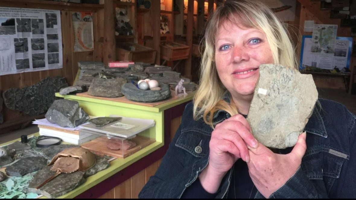 sonja-wood-blue-fossil-museum-horseshoe-crab A woman smiles and holds up a fossil.
