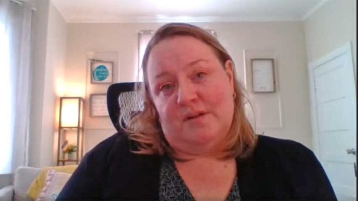 stacie-quigley-cormier-patient-advocate-dalhousie-junction A woman with straight, blond, shoulder-length hair, wearing a dark blouse and black cardigan, sitting in an office chair, talking.