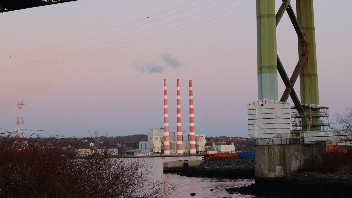 tufts-cove-generating-station-nova-scotia-power Three iconic stacks of the Tufts Cove generating station are seen across the Halifax harbour. A bridge is in the frame and the sun has nearly set.