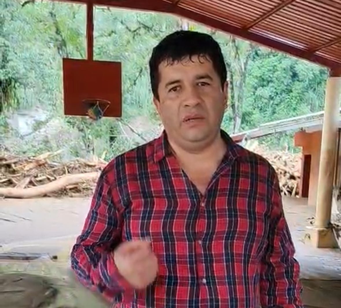 A man with dark hair wearing a plaid shirt.