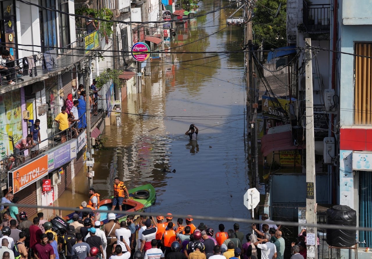 default-32 A man wades through a flooded street as people watch from buildings