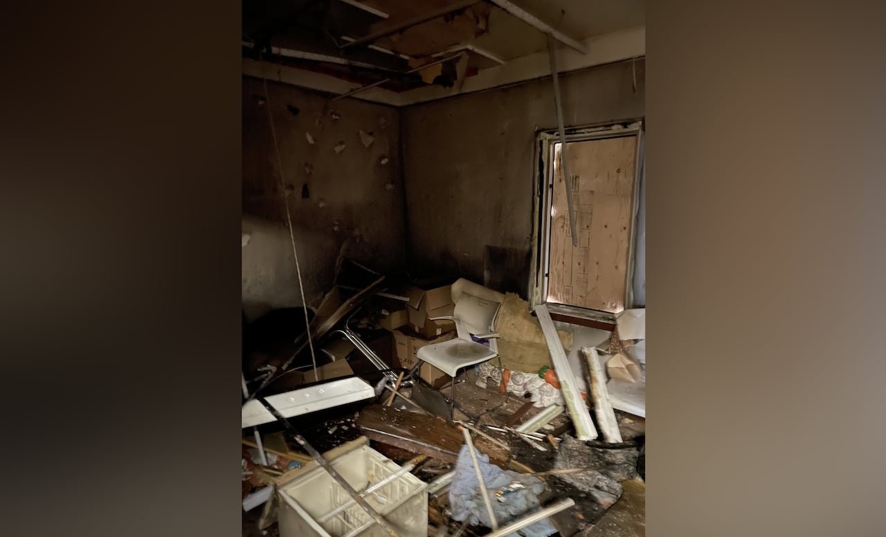 Furniture and other items are scattered across an office floor with a boarded-up window.