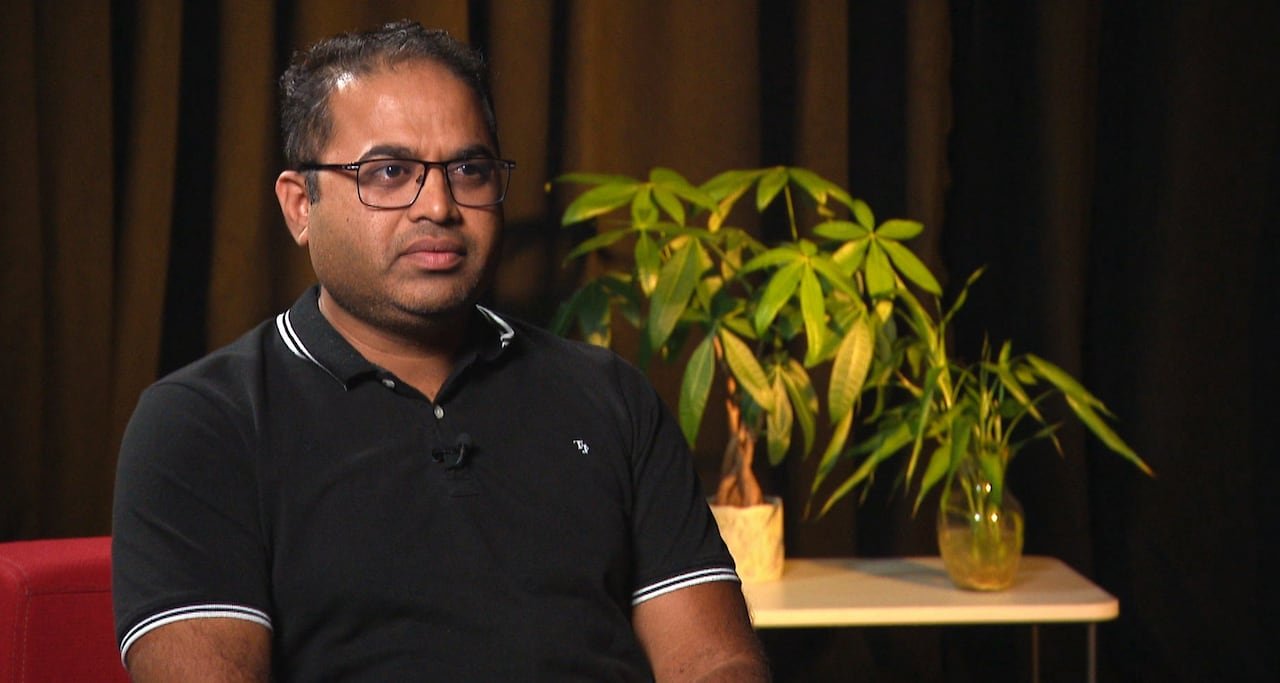 default-524 Man sitting in red chair with plants behind him