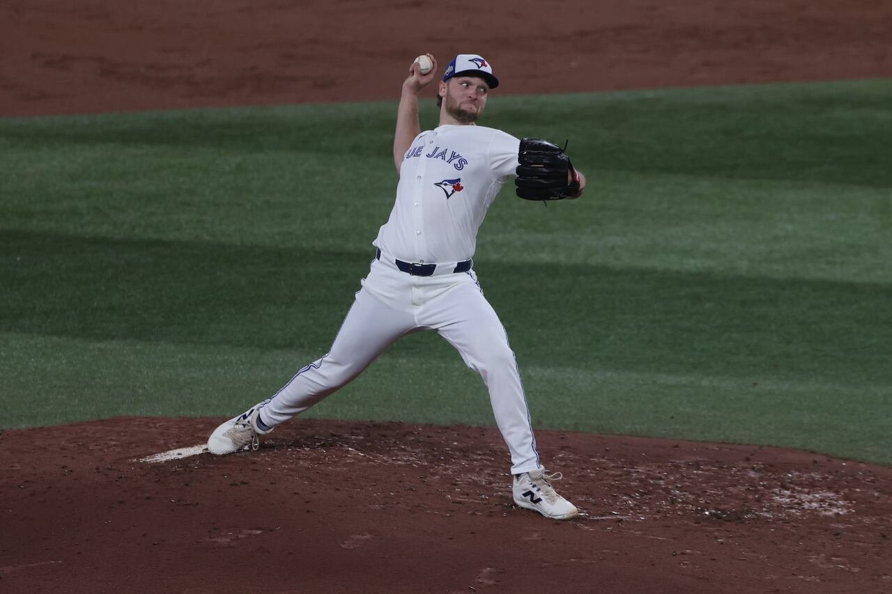 A player in white pulls his arm back to pitch.