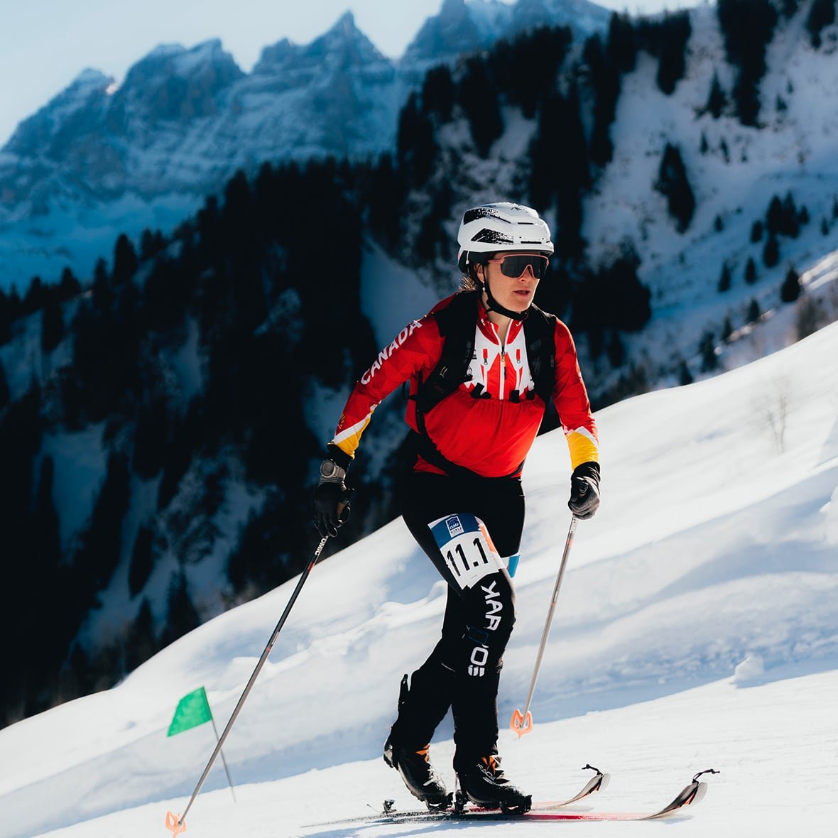 default-49 A women's skier climbs a ski hill with a mountain range in the background.