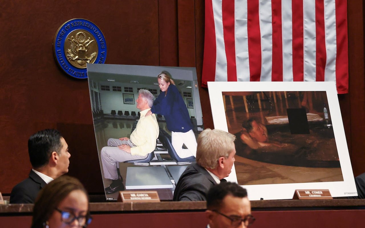 default-166 Two large photos of Bill Clinton are propped up on a desk while men in suits look on