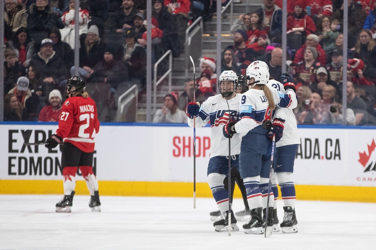 default-5 American hockey players celebrate on the ice, while the Canadians look on.