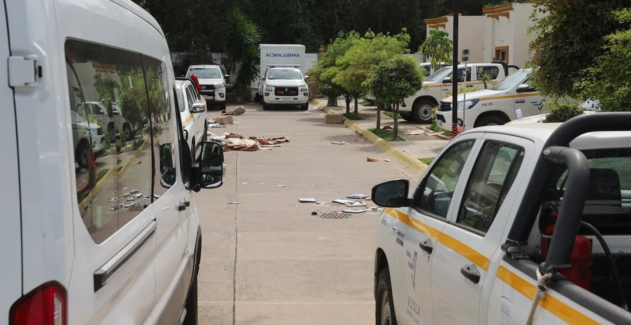 White vans and pickup trucks parked in a parking lot with cardboard strewn around.