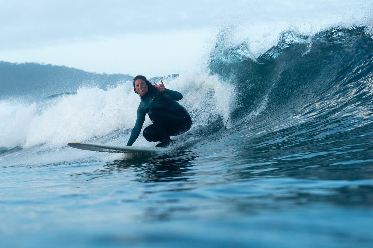 default-518 A woman surfing in the winter looks at the camera as she surfs by.